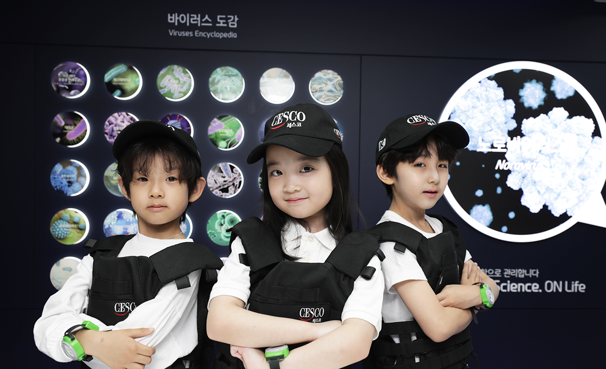 키자니아 세스코 체험을 하고 있는 아이 세명이 팔짱을 끼고 있습니다.